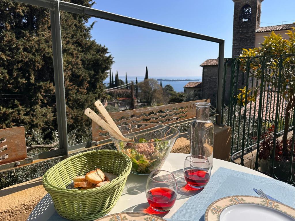 a table with a basket of food and two glasses of wine at Seeblick VILLA LAGUNA BLUE - Private Spa - Whirlpool & Sauna in Gardone Riviera