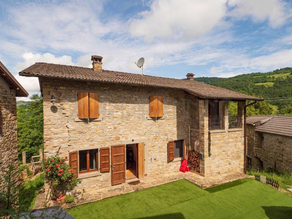 a woman sitting in front of a stone house at Perbone 1573 - Premium Restored Villa in Toano