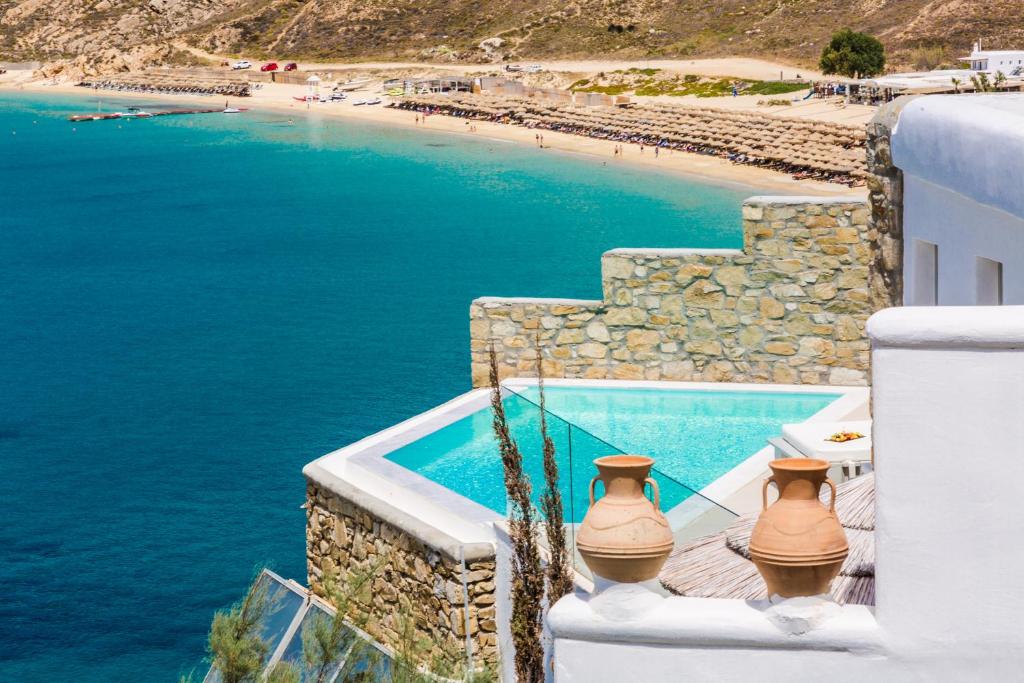 a swimming pool next to a beach with two vases on a building at Greco Philia Hotel Boutique by Mr and Mrs White in Elia Beach