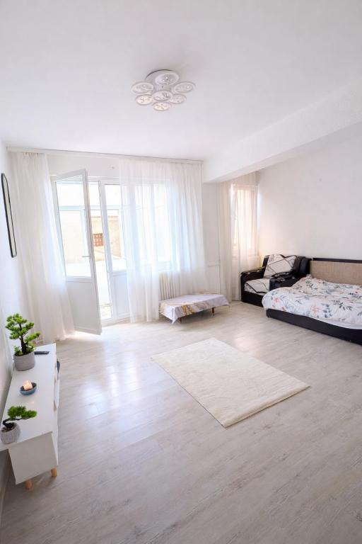 a white room with a bed and a table at Ploiești Centru in Ploieşti