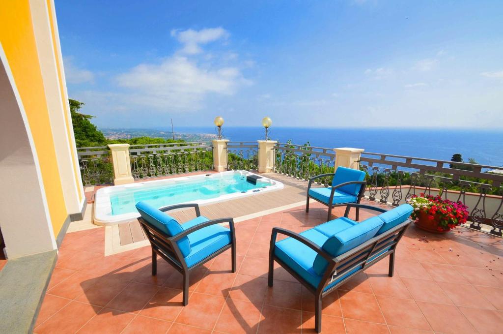 un patio con 3 sedie e una piscina di Villa La Timpa - antica e maestosa villa con jacuzzi privata con una meravigliosa vista sull'Etna e sul mare ad Acireale