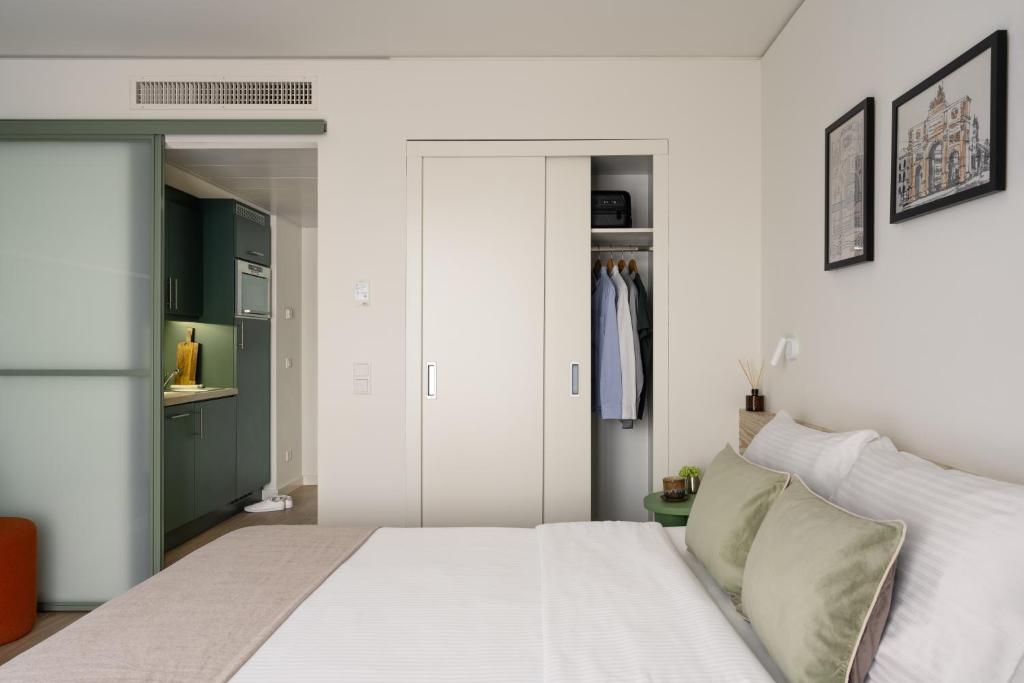 a bedroom with a white bed and green cabinets at Bob W Munich City Centre in Munich