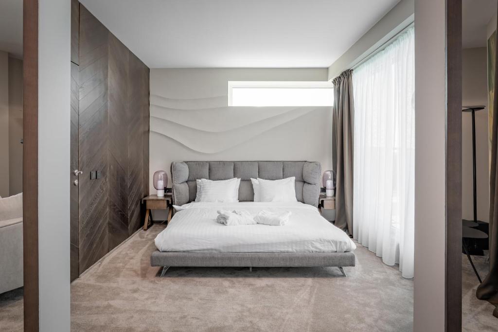 a bedroom with a white bed with two stuffed animals on it at Dunetton - self check-in hotel in Klaipėda