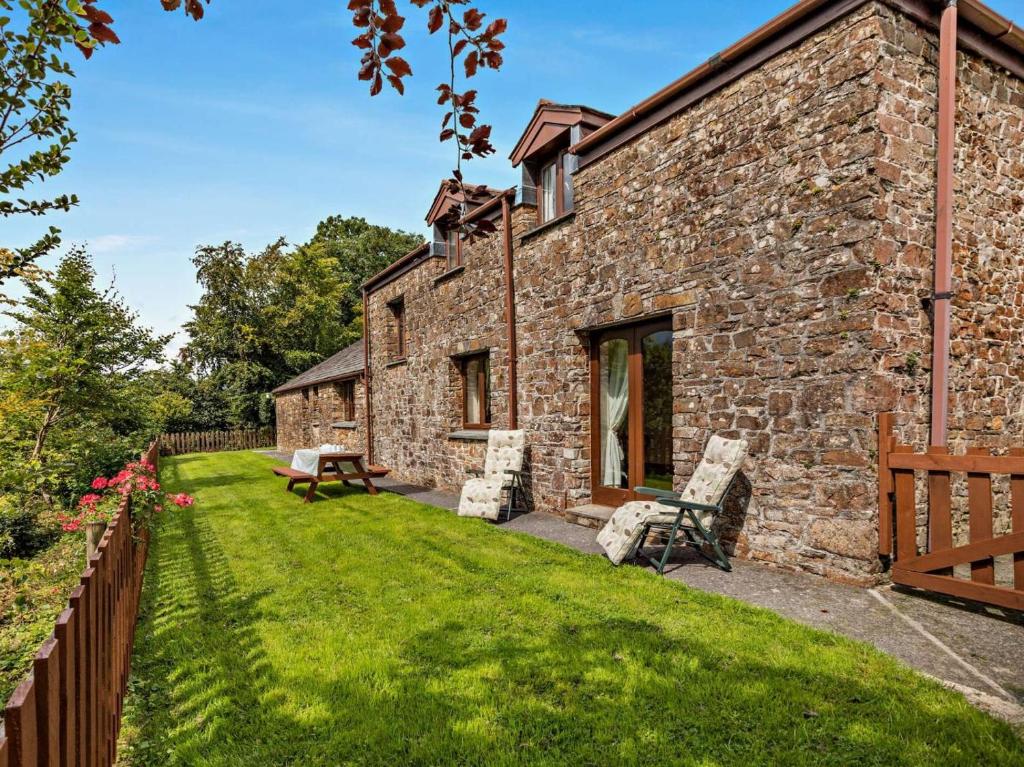 a stone house with a green yard with two chairs at 4 Bed in Holsworthy oc-lamer in Merryfield