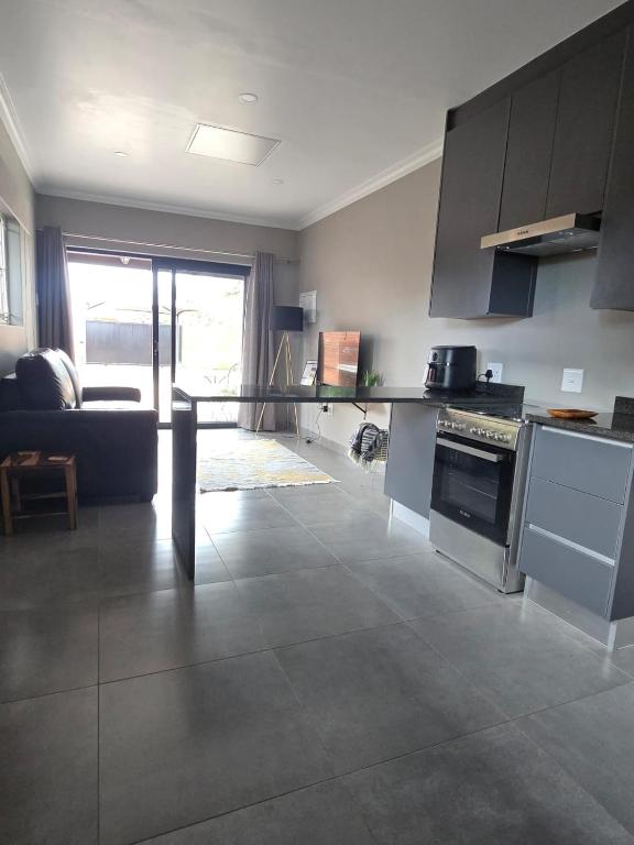 a living room with a kitchen and a couch at The Oak GuestUnit in Kathu