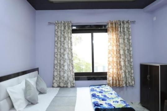 a bedroom with a bed and a large window at Hotel Jaanvi in Orchha