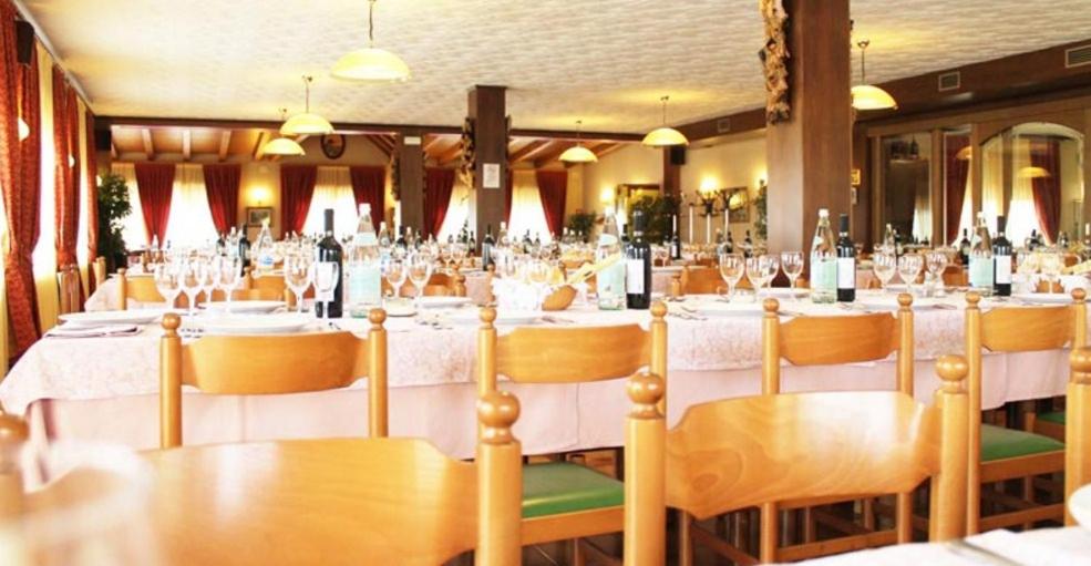 uma sala de jantar com mesas e cadeiras com copos de vinho em Due Mori em Roana