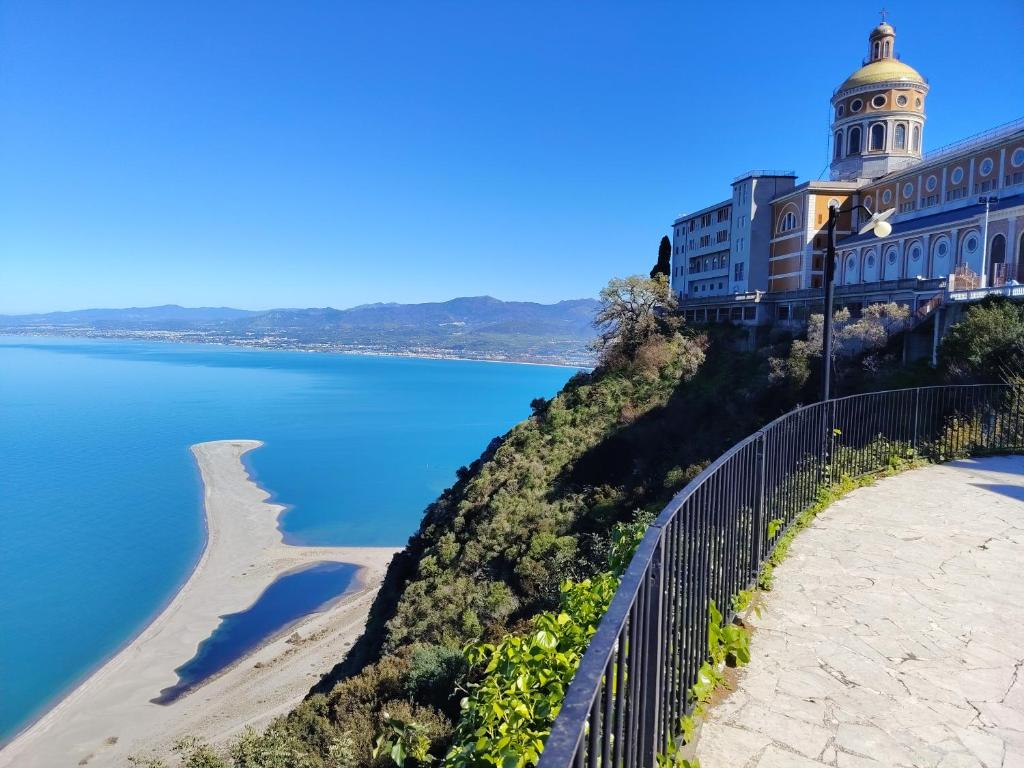 a building on top of a hill next to a body of water at Sweet Home in Oliveri