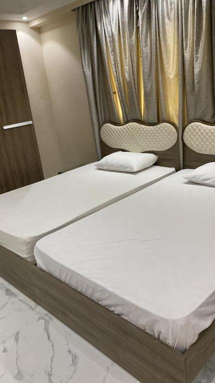 two twin beds in a room with curtains at H&d abrrtment hotel 5 in Cairo