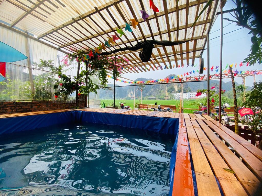 a large swimming pool with a wooden deck and an outdoor patio at Tam Coc Big J hostel in Vũ Lâm