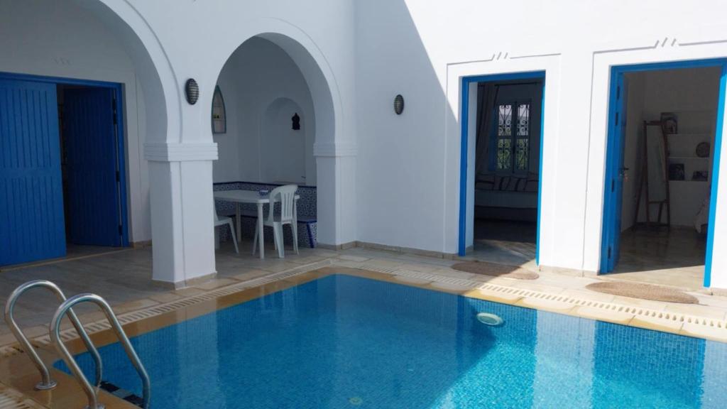 a house with a swimming pool in a room at Menzel à Midoun in Al Maqārisah
