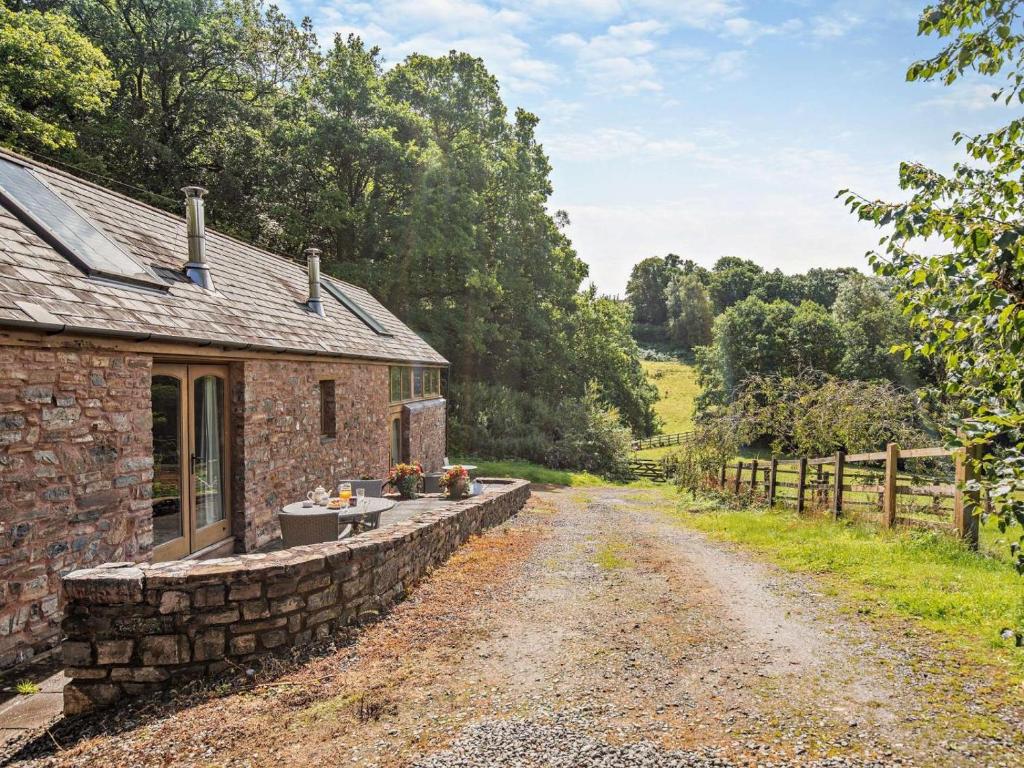 a stone house with a stone wall next to a dirt road at 1 Bed in Bampton oc-limkc in Bampton