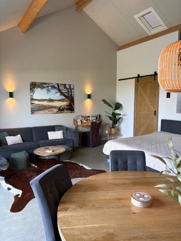 a living room with a bed and a wooden table at Weidezicht Soest, beauty & wellness en rust & natuur in Soest