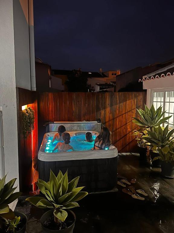 two children in a hot tub in a backyard at night at Azor International House in Ponta Delgada