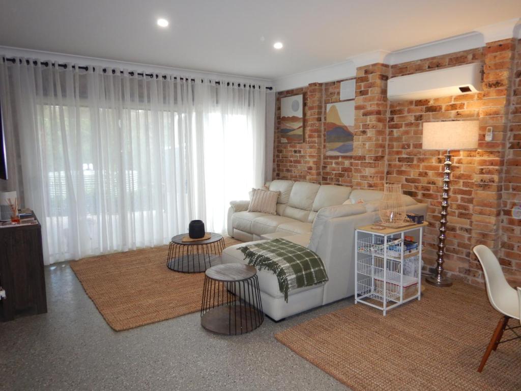a living room with a couch and a brick wall at The Honeypot in Balmoral