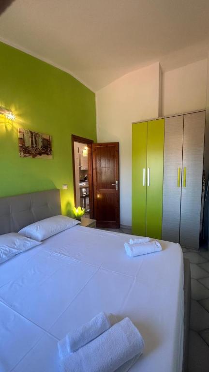 a bedroom with a large white bed with green walls at Casa Rita in San Teodoro