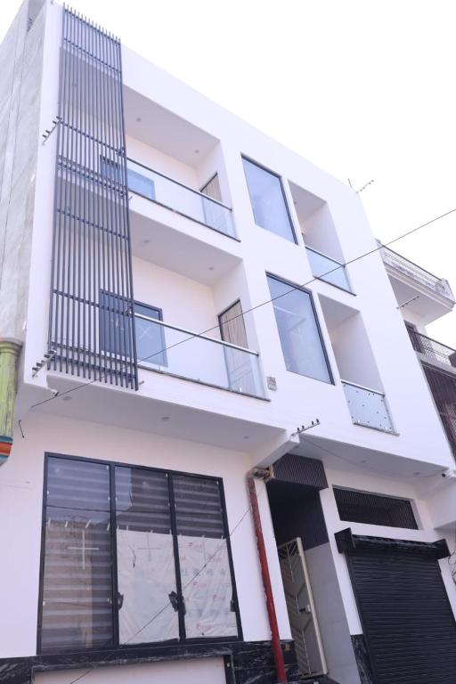 a white building with windows and a balcony at Aachman Restaurent in Bulandshahr
