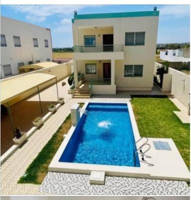 a large swimming pool in front of a house at Villa D'or in Ḩammām al Ghazzāz