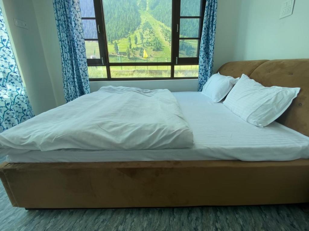 a bed with white sheets and a window with a view at Gurez knights in Kanzalwan
