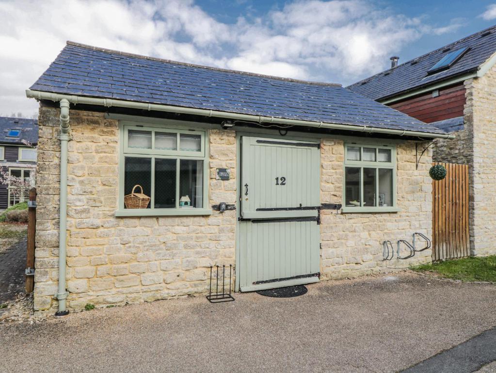 a small brick house with a door and a window at Firefly Cottage in Cirencester