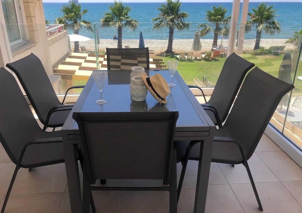a dining table and chairs with a view of the beach at Seafront Escape Apartment in Oroklini