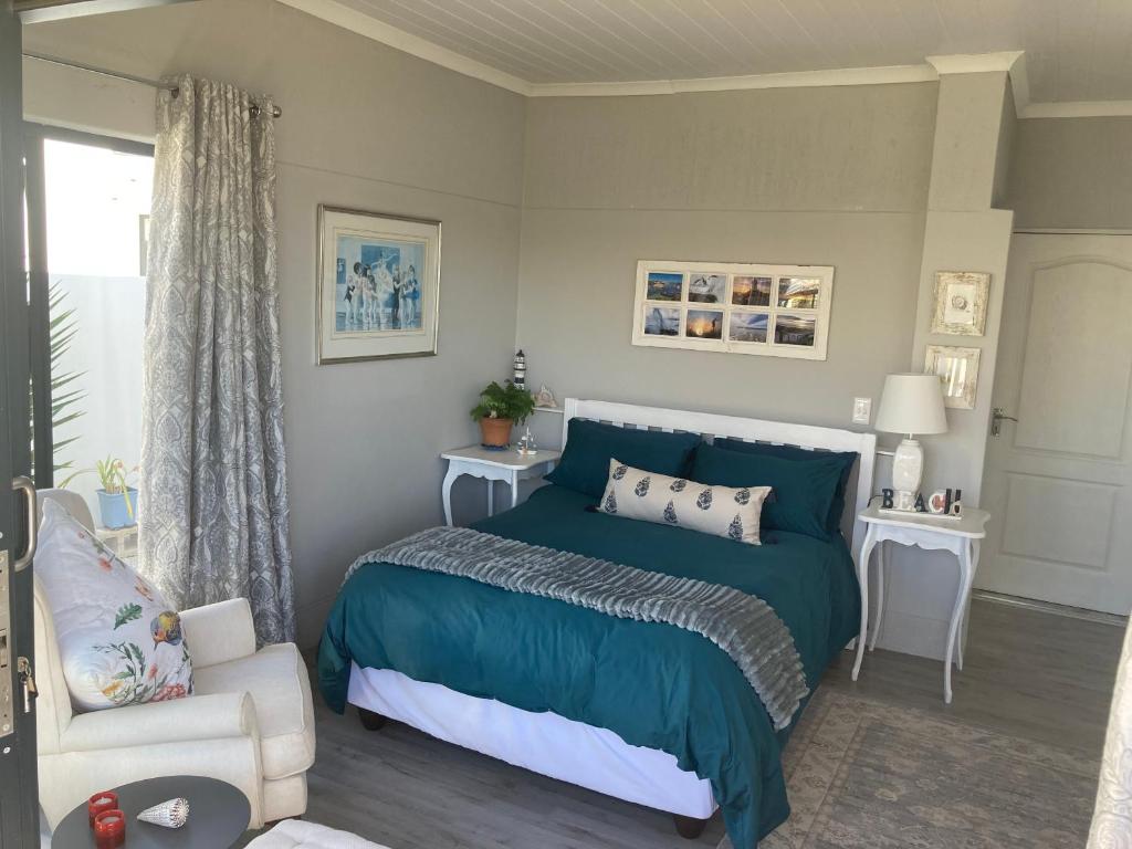a bedroom with a blue bed and a chair at Shelley Cove in Stompneusbaai