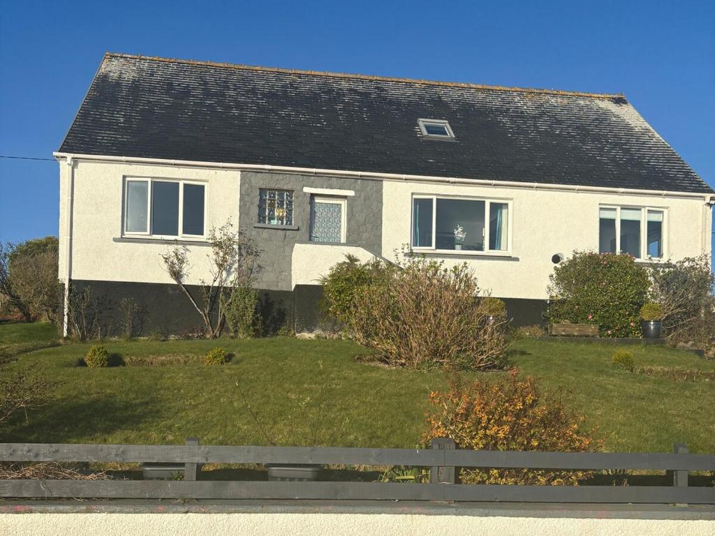 a white house with a black roof on a yard at 3 Linshader in Callernish