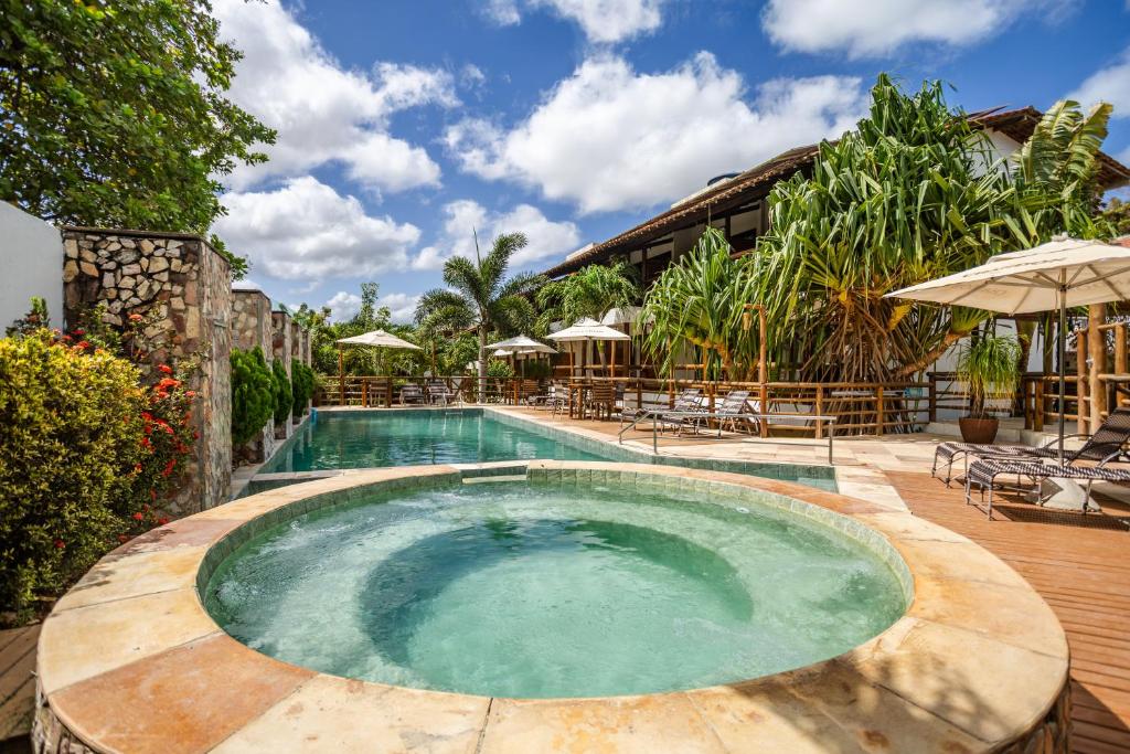 a swimming pool with chairs and umbrellas at a resort at Pousada Carcará - JERI in Jericoacoara