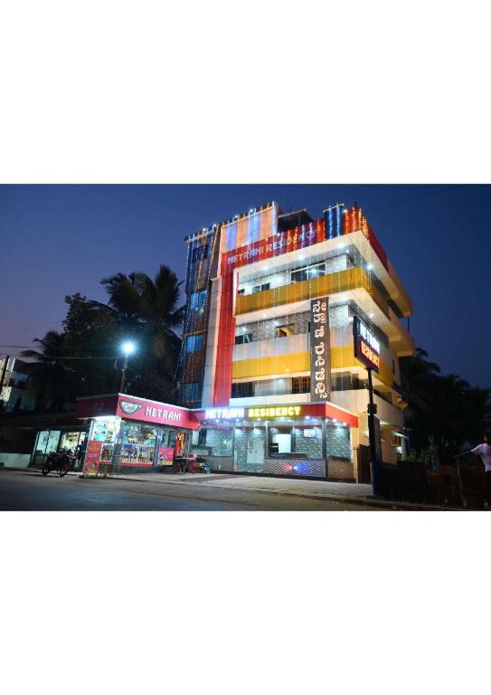 a tall building on a city street at night at Netrani Residency in Māvalli