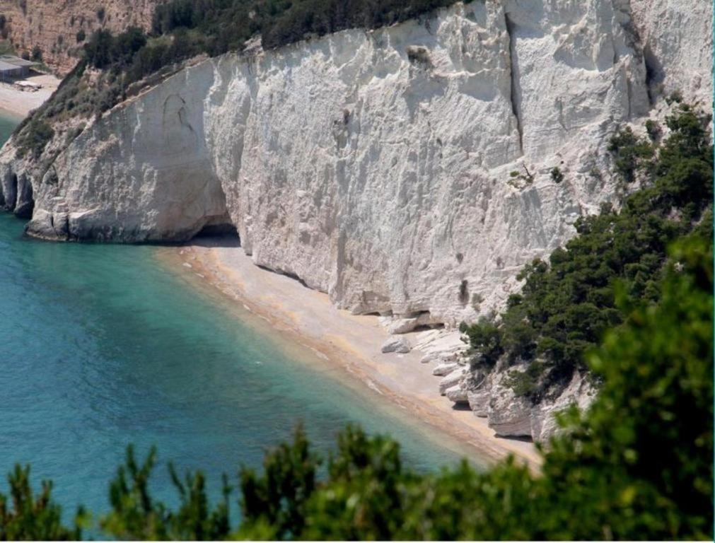 a sandy beach next to a large rock cliff at Casaverde Gargano in Mattinata