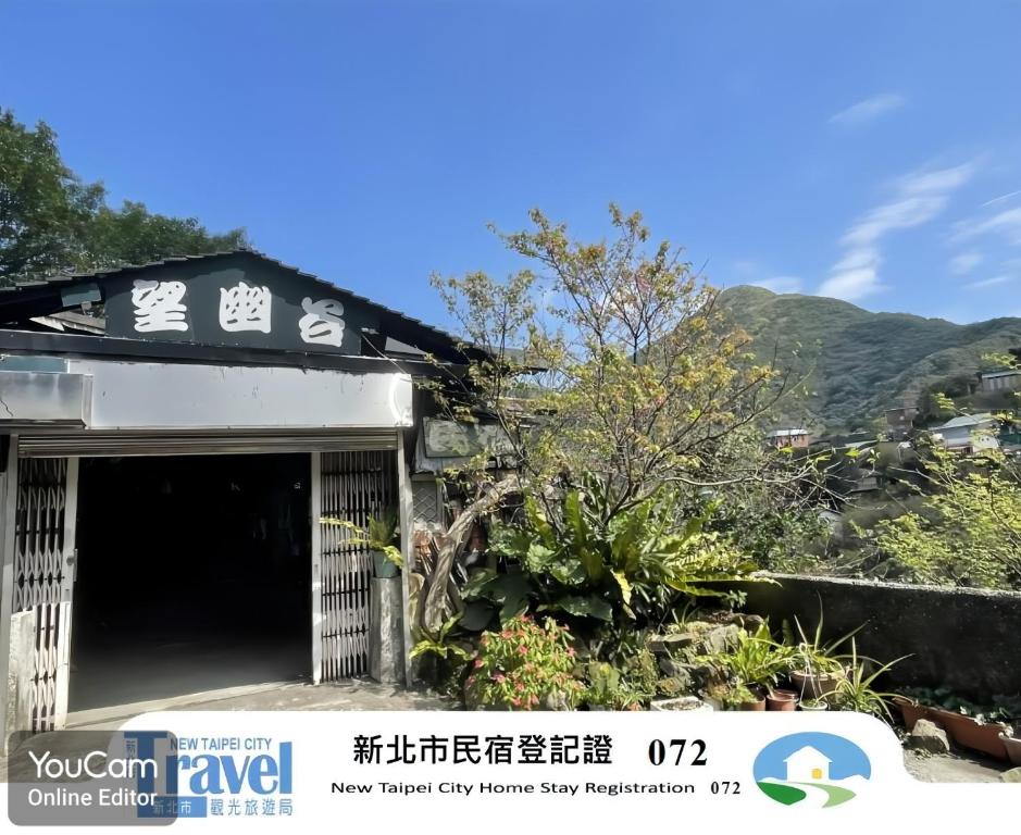 a building with a garage with a mountain in the background at Wangyuku B&B in Jiufen