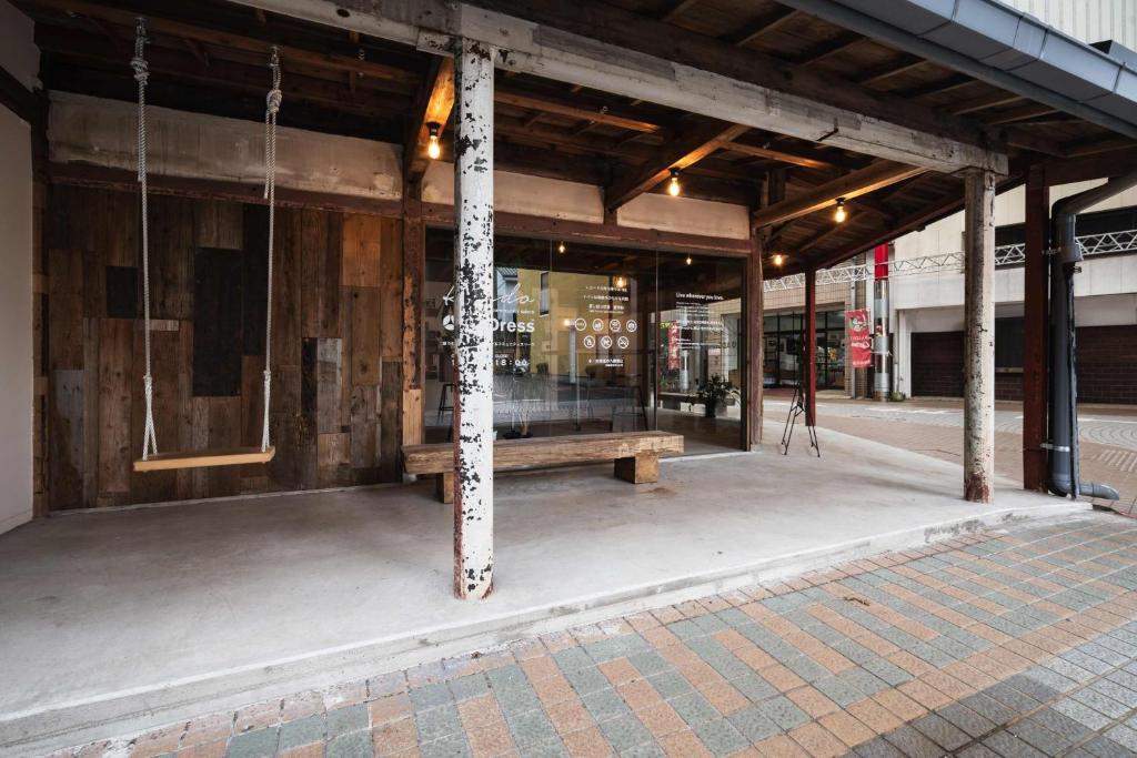 a building with a bench in front of a store at Aburatsu Inn Kadocco in Nichinan