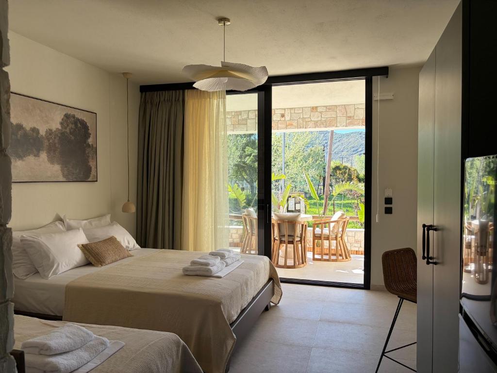 a bedroom with two beds and a sliding glass door at Noima Kalamitsi Boutique Studios in Kalamitsi
