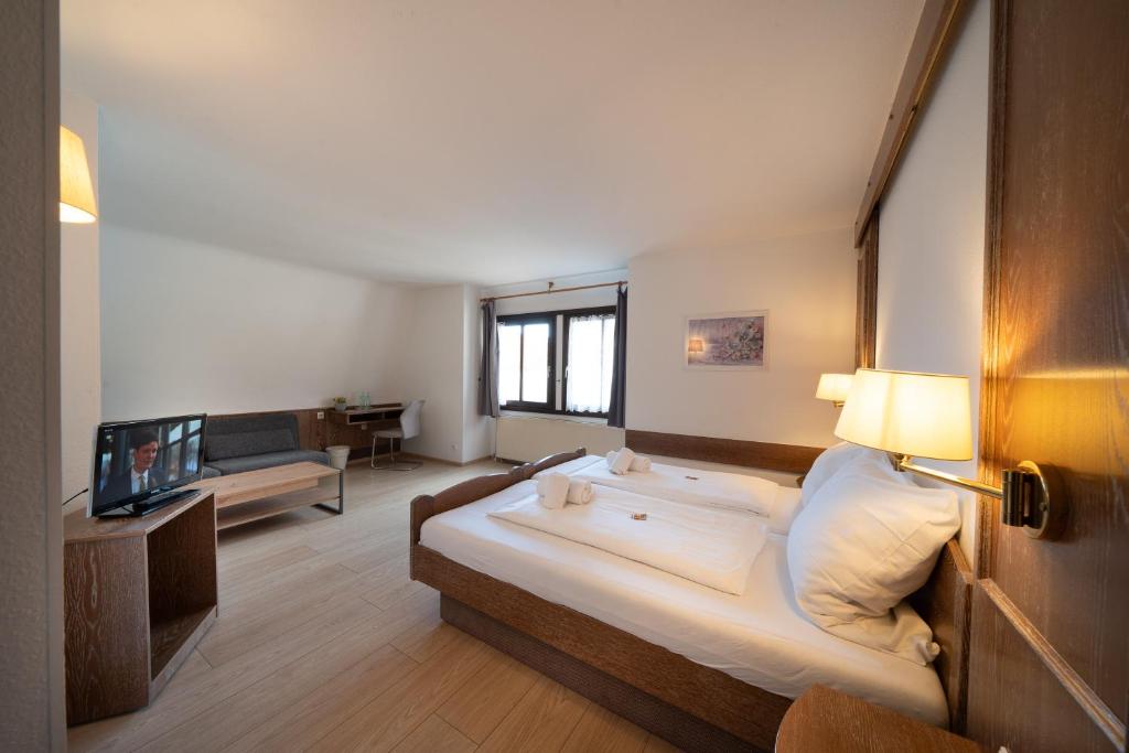 a bedroom with a large bed and a living room at Hotel Baeren in Leimen