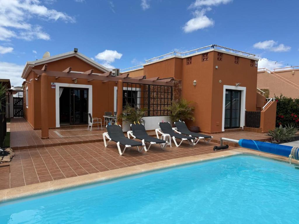 a house with a swimming pool in front of a house at Casa Piedra, Luxury Family Front Line Golf, Hot Tub,Pool Table, 8 pers, Caleta de Fuste in Caleta De Fuste