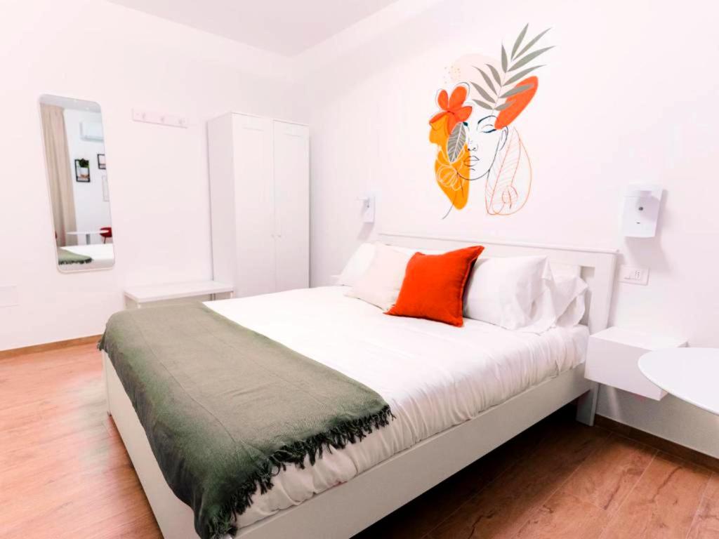 a white bedroom with a bed with an orange pillow at La tana del Furlo in Acqualagna