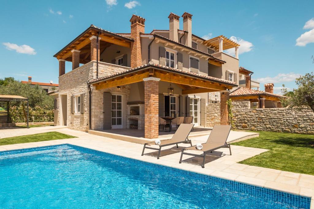 a villa with a swimming pool in front of a house at Villa Natalie in Vabriga