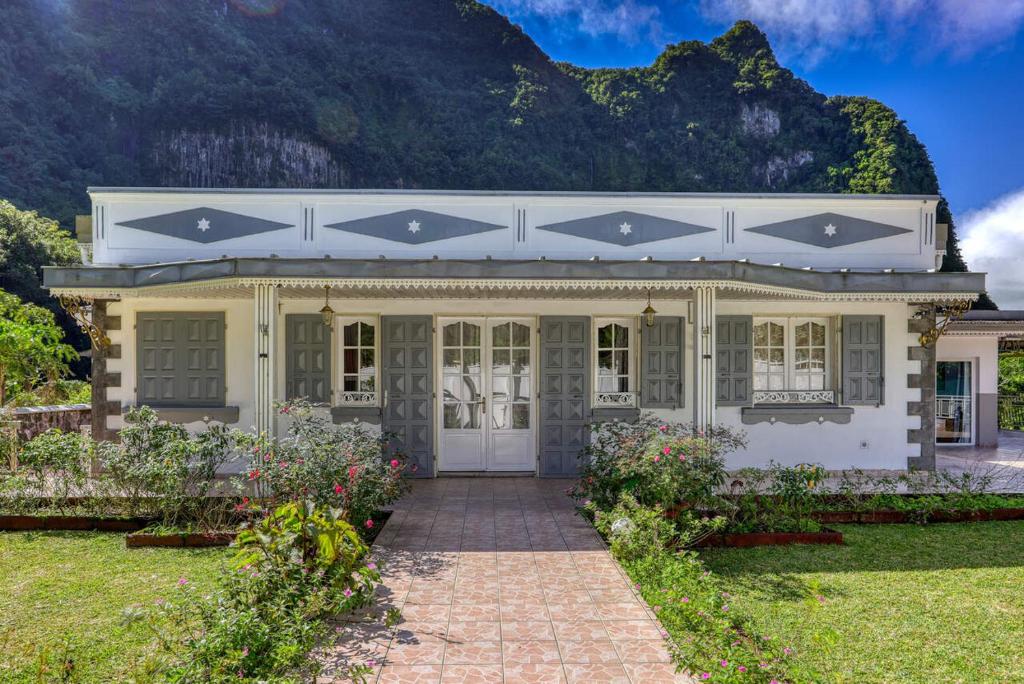 a white house with a mountain in the background at L'Escale Royale in Salazie
