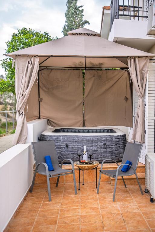 a patio with two chairs and a table and an umbrella at Villa Stella with Jacuzzi in Oroklini