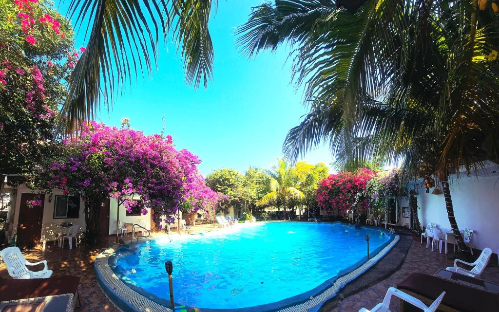 a large swimming pool with palm trees and pink flowers at OASIS Phuket Airport in Nai Yang Beach