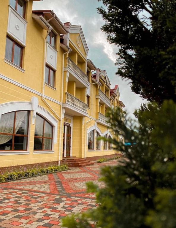 a large yellow building with a red brick courtyard at Сонячна Квітка in Polyana
