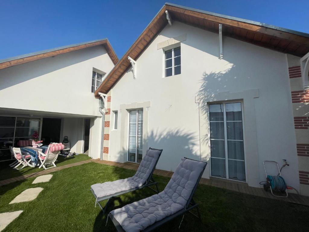 a patio with two chairs and a table on a lawn at Arcachonnaise 5 chambres, 500M de la plage et 6 vélos à disposition in Arcachon