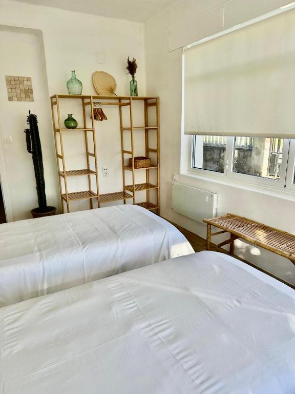 a bedroom with two white beds and a window at Casa Maruxa in Valdoviño
