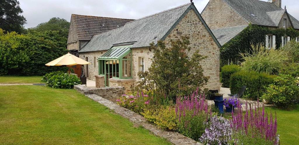 a house with an umbrella and a garden with flowers at Gîte G175 in Grosville
