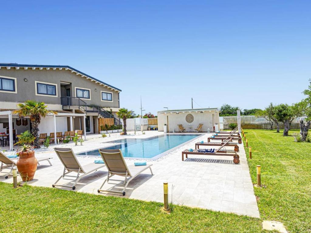 a swimming pool with chairs and a house at Villa Kika by holiday World in Ispica