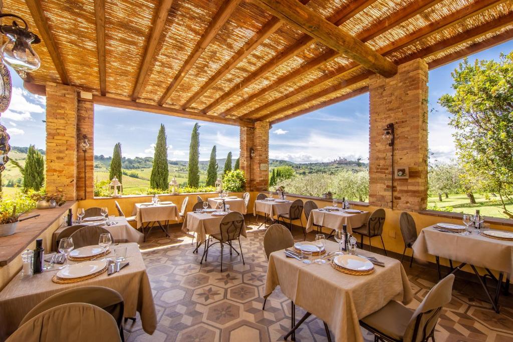a restaurant with tables and chairs and a large window at Agriturismo Il Segreto di Pietrafitta in San Gimignano