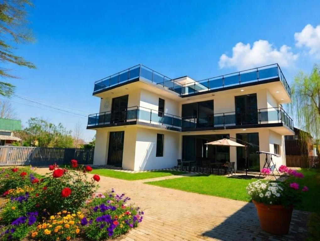 a white house with a balcony and some flowers at Villa White Dolphin Kaprovani in Ureki