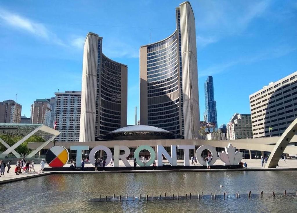 a city with a sign that reads tomorrow in front of buildings at FIFA CENTRAL TORONTO-DIRECT TO BMO FIELD-Live Game Atmosphere-Free Wifi in Toronto