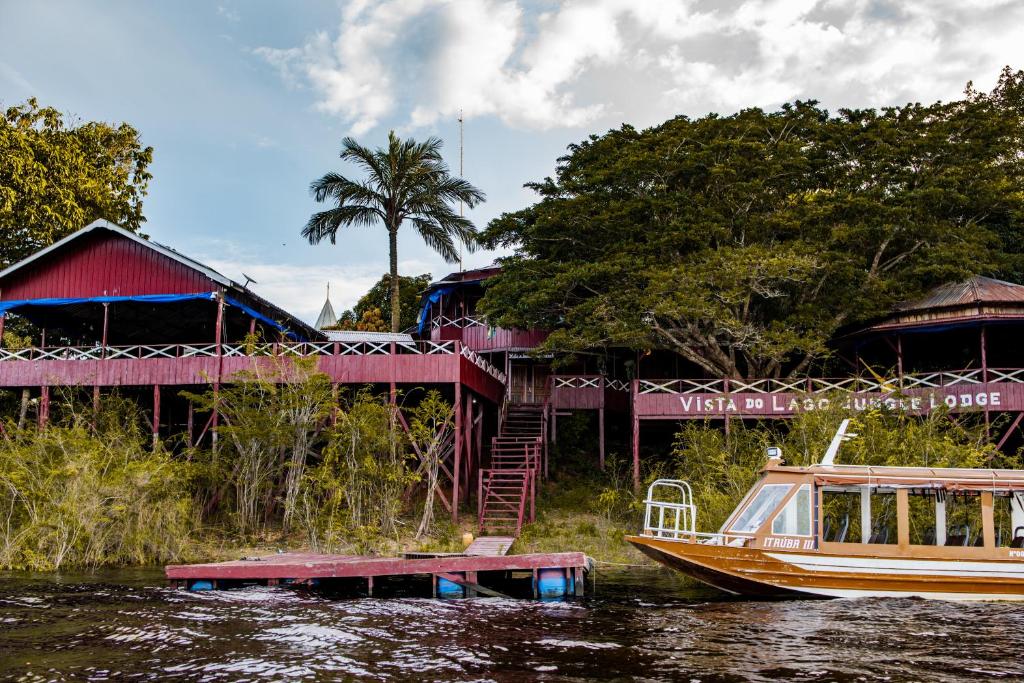 a boat in the water next to a building at Vista do Lago Jungle Lodge in Cajual