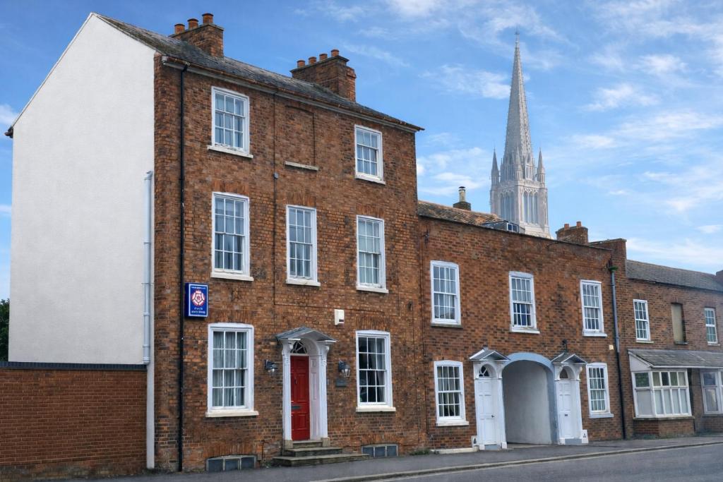 an old brick building with a church in the background at The Red House Guest House in Grantham
